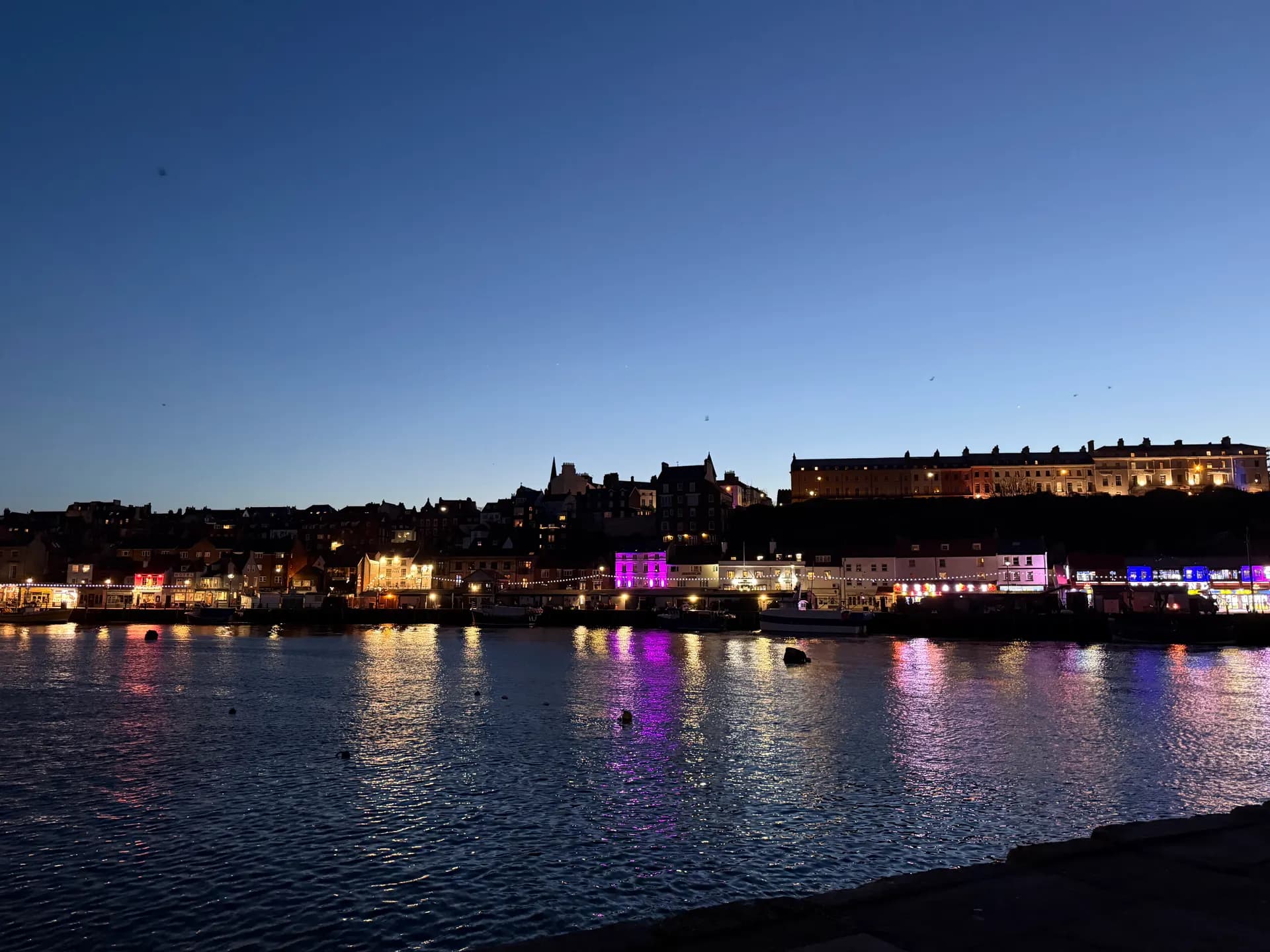 Whitby harbour lights reflected on the water at twilight