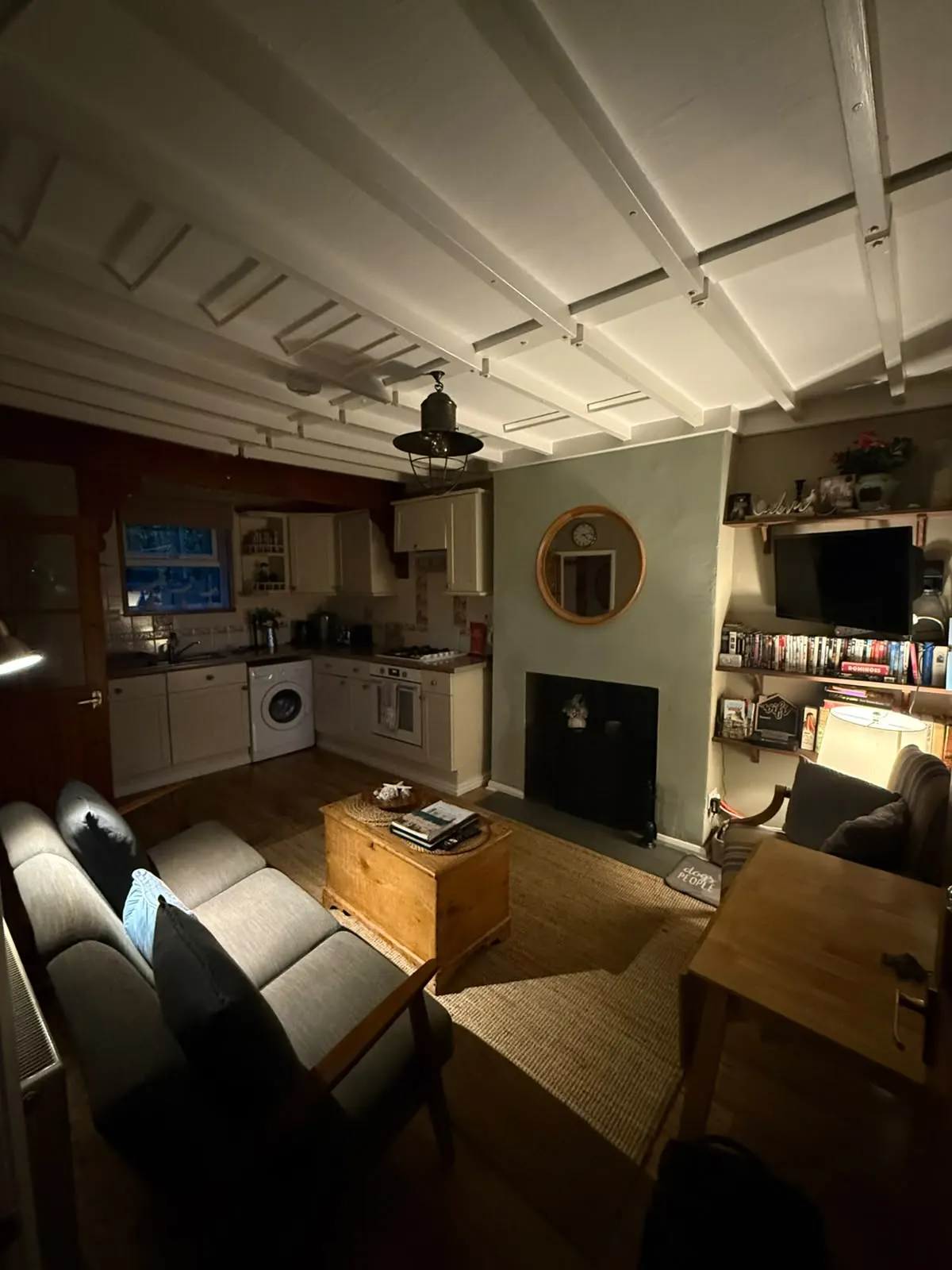 Open-plan sitting room and kitchen with a log burner and beamed ceiling