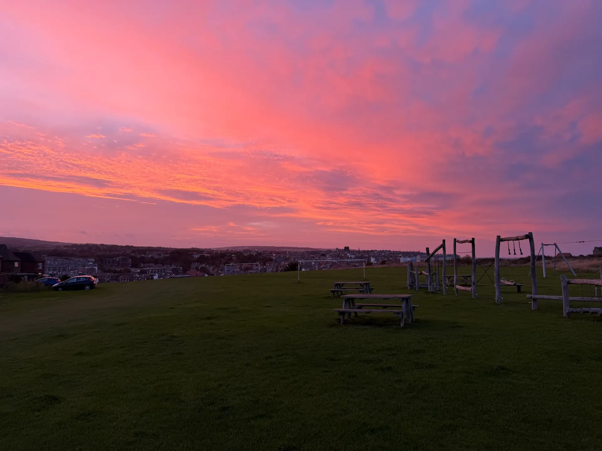 Pink sunset sky over Whitby from a clifftop field